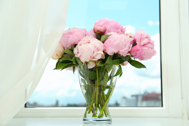Photo of Bouquet of beautiful peonies in vase on window sill
