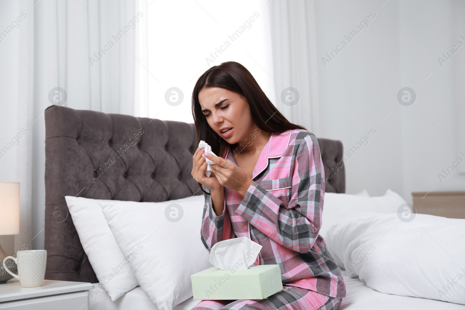 Photo of Young woman suffering from allergy in bedroom