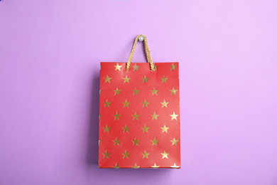 Photo of Red shopping paper bag with star pattern on violet background