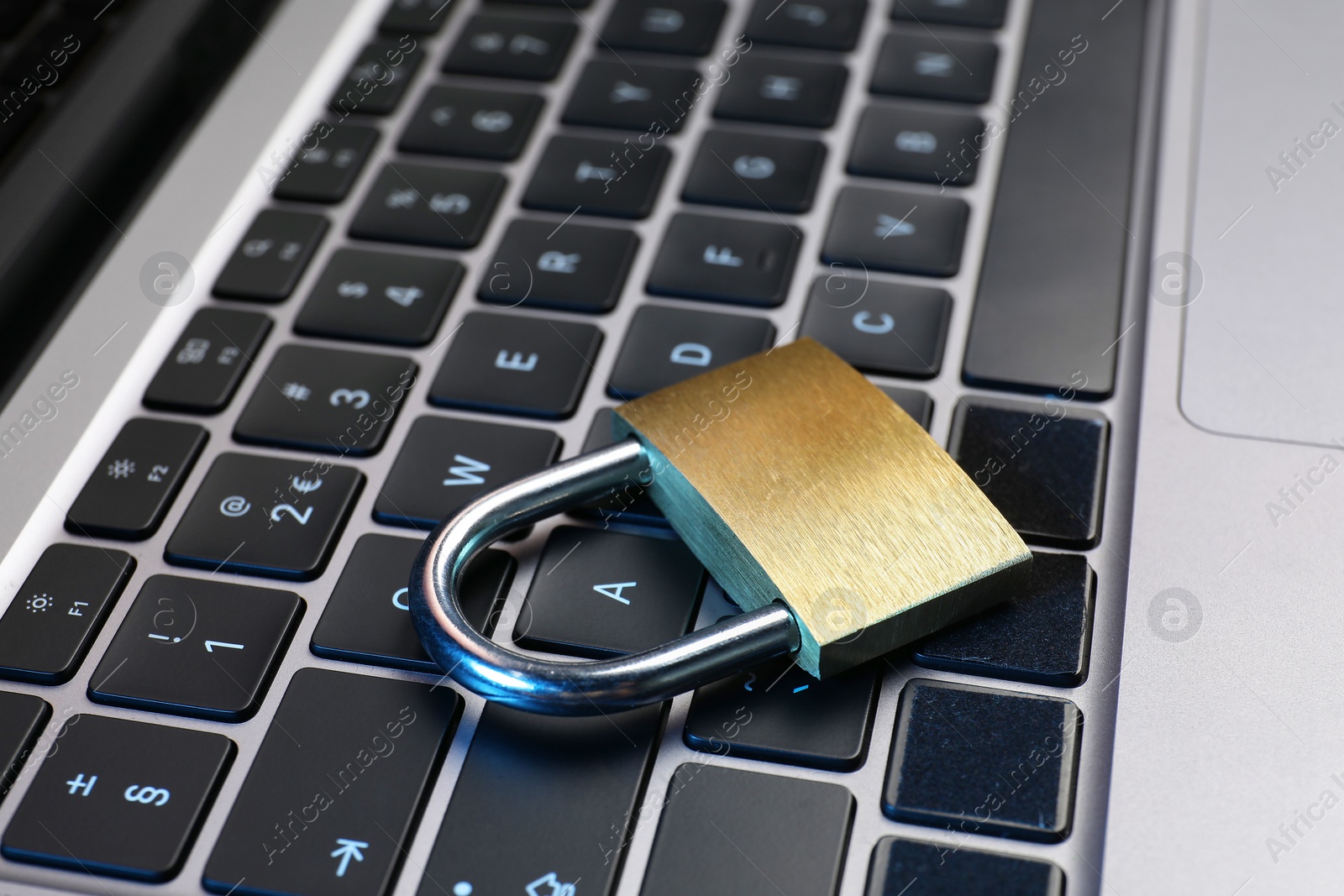 Photo of Cyber security. Metal padlock on laptop, closeup