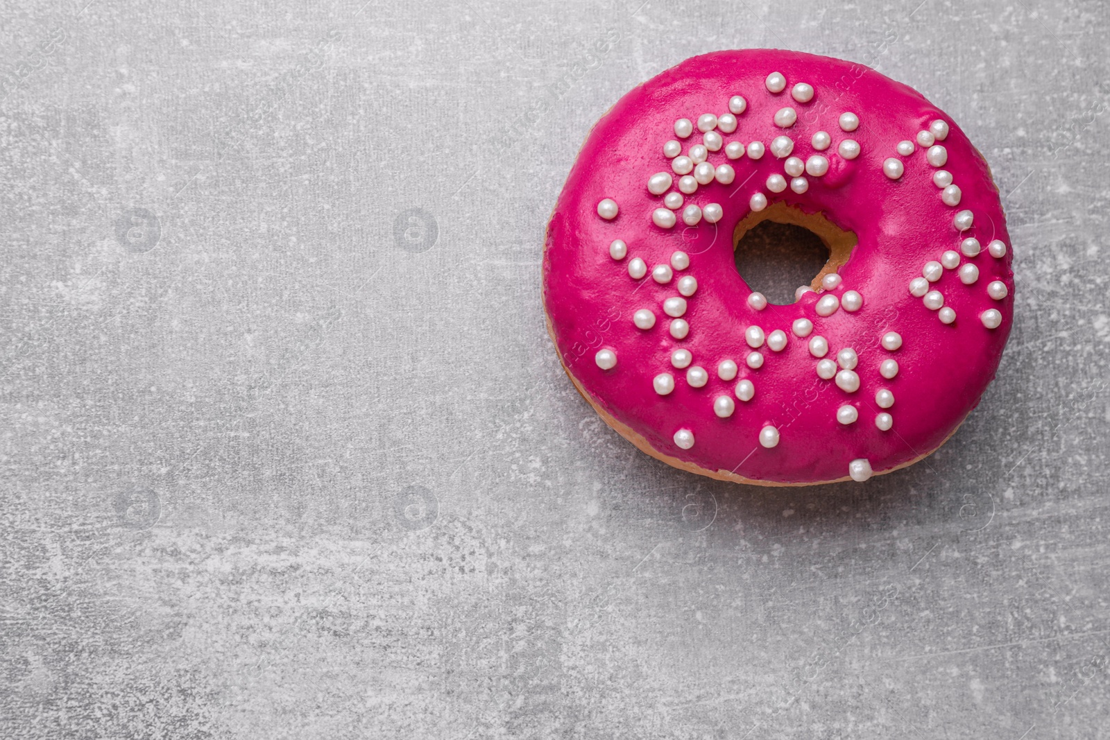 Photo of Tasty glazed donut decorated with sprinkles on light grey table, top view. Space for text