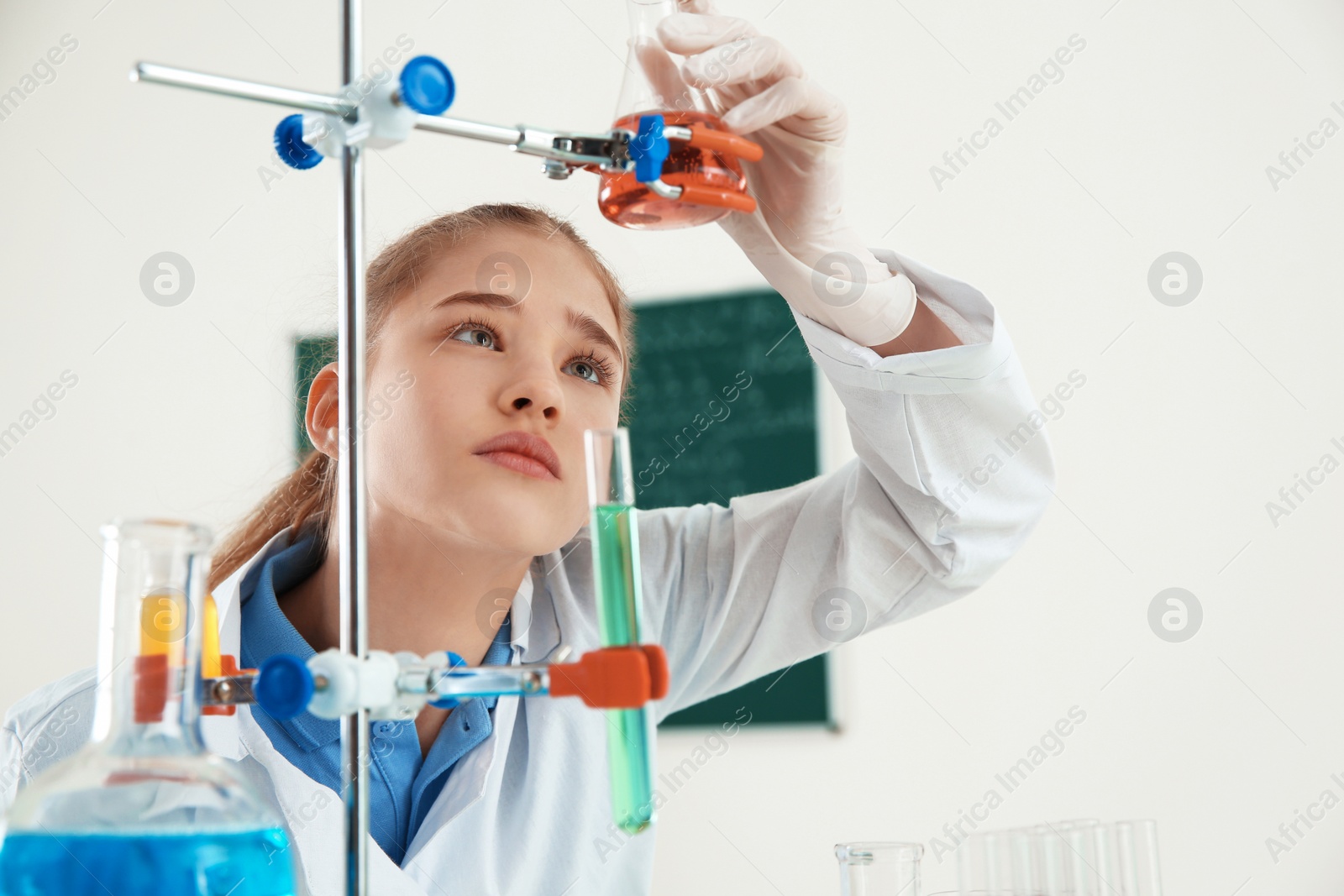 Photo of Smart pupil looking at flask with reagent on holder in chemistry class