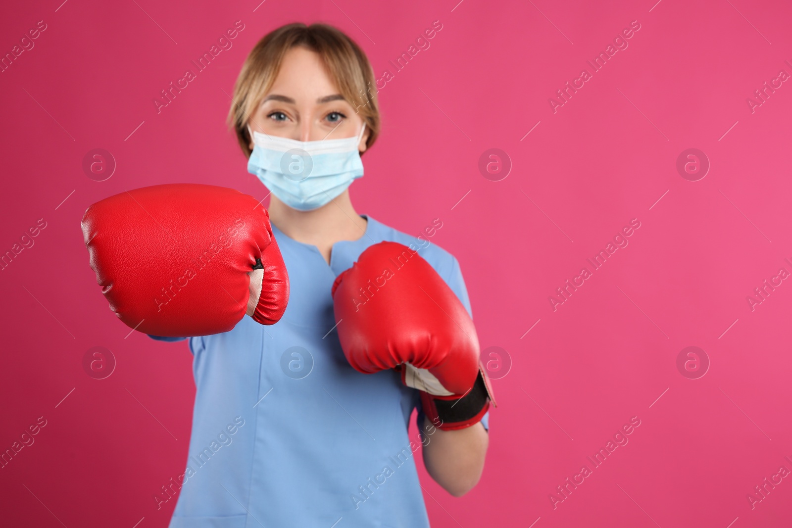 Photo of Doctor with protective mask and boxing gloves on pink background, space for text. Strong immunity concept