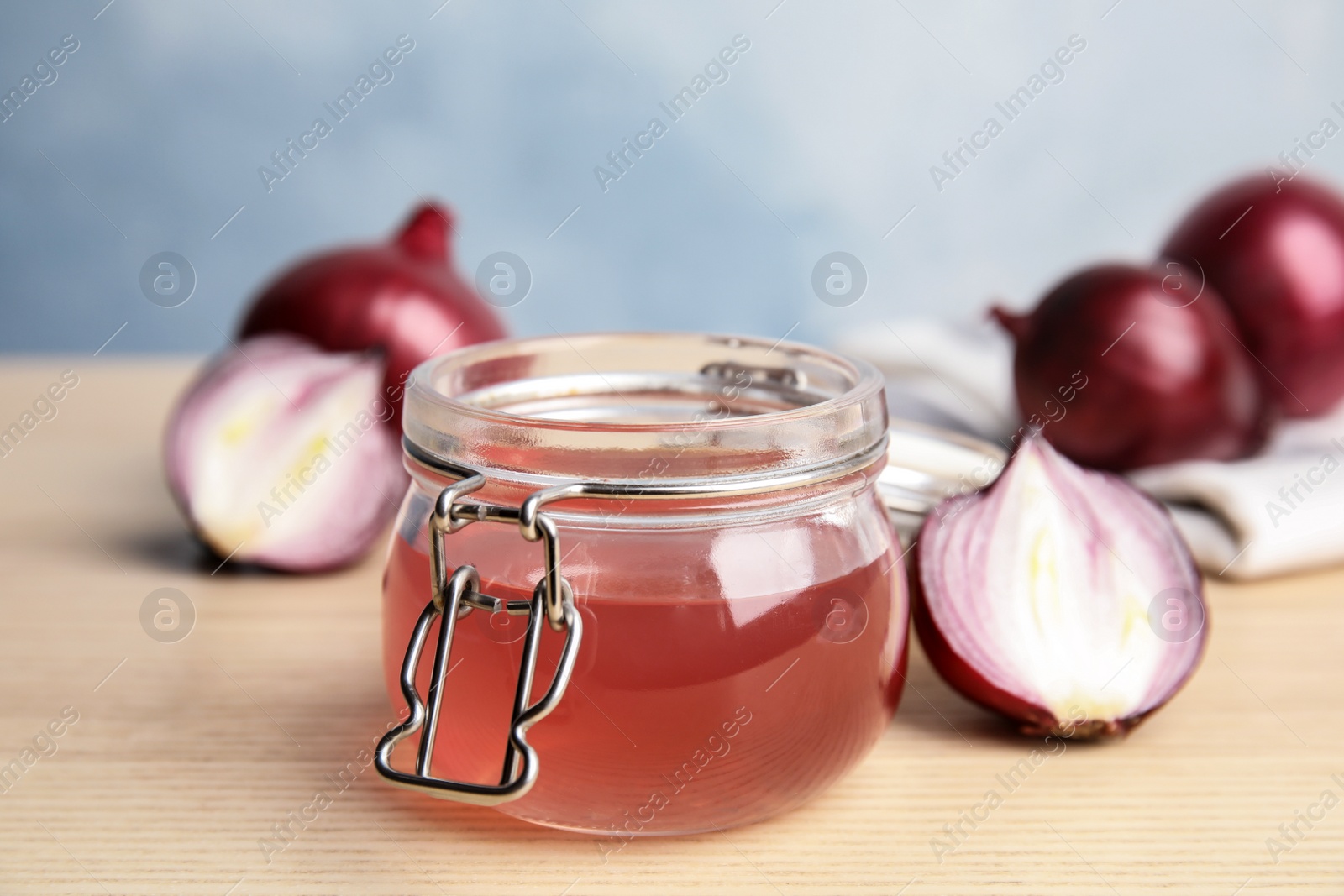 Photo of Glass jar with onion syrup and fresh ingredient on wooden table