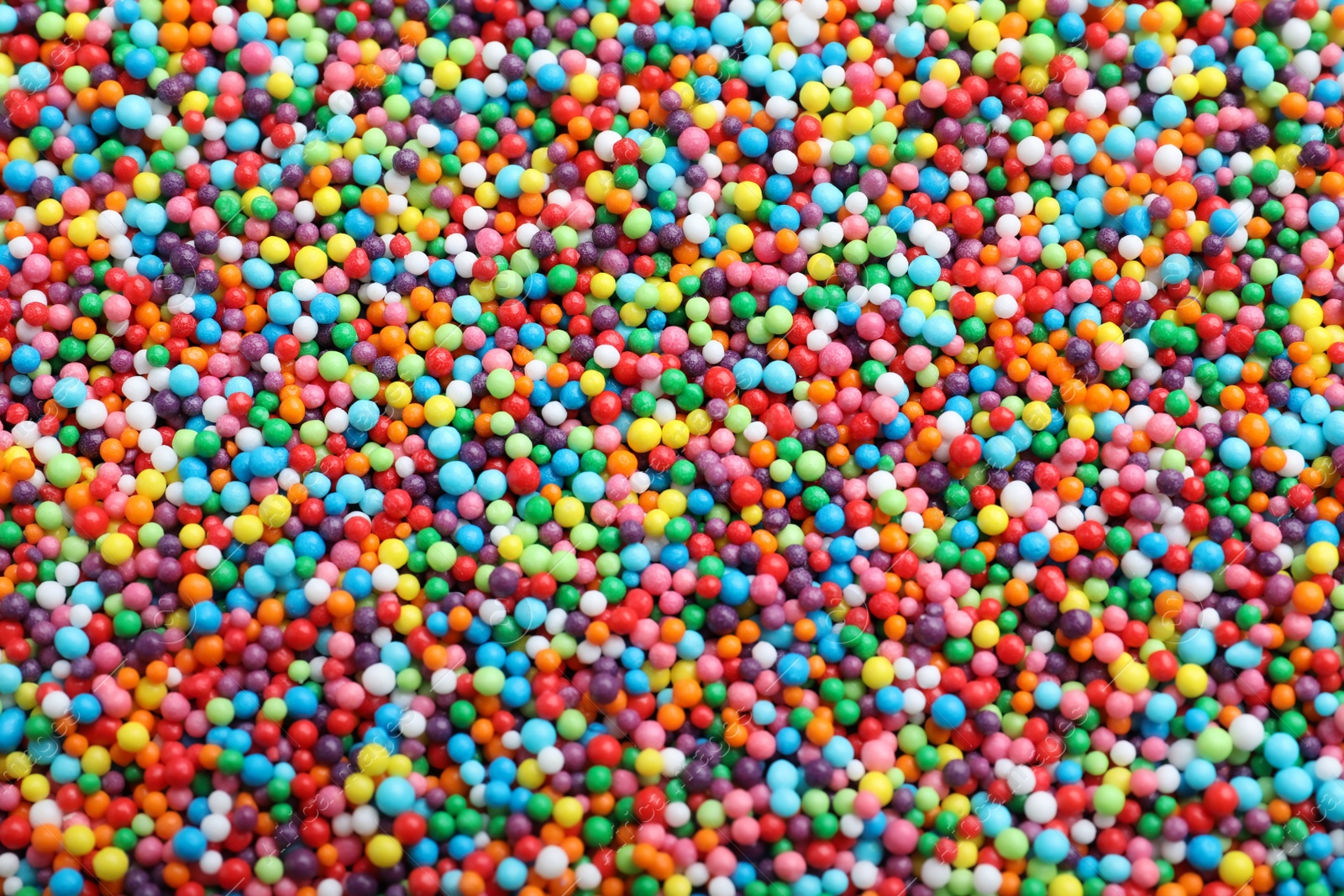 Photo of Bright colorful sprinkles as background, top view. Confectionery decor