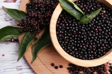 Photo of Tasty elderberries (Sambucus) on white wooden table, top view