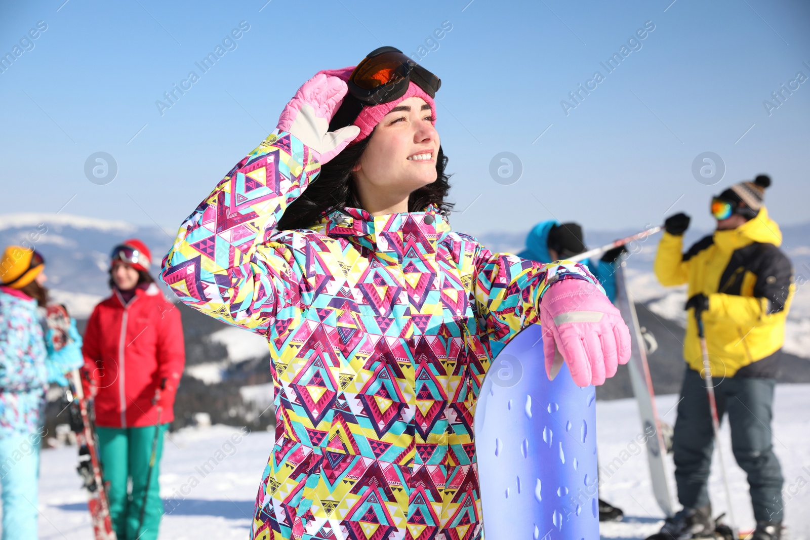 Photo of Young woman with snowboard at ski resort. Winter vacation