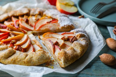 Photo of Delicious apple galette and pecans on wooden table, closeup