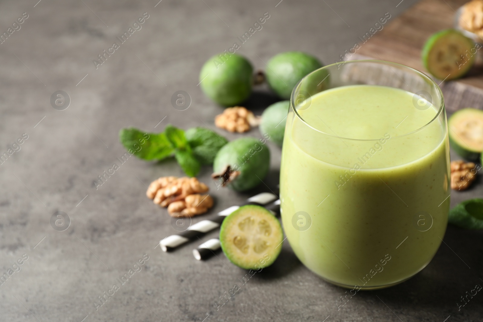 Photo of Fresh feijoa smoothie in glass on grey table, space for text