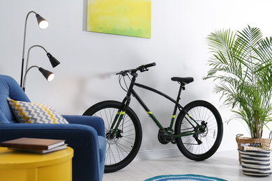 Photo of Modern bicycle and comfortable armchair in stylish living room interior