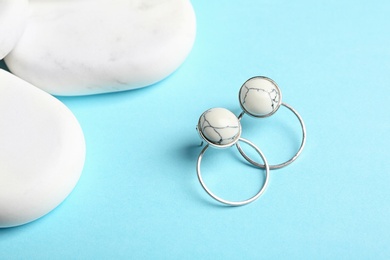 Photo of Elegant earrings and white marble on light blue background. Luxury jewelry
