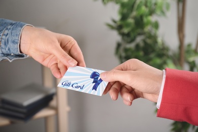 Women with gift card on blurred background, closeup 