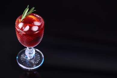 Photo of Glass of delicious refreshing sangria on black table, space for text