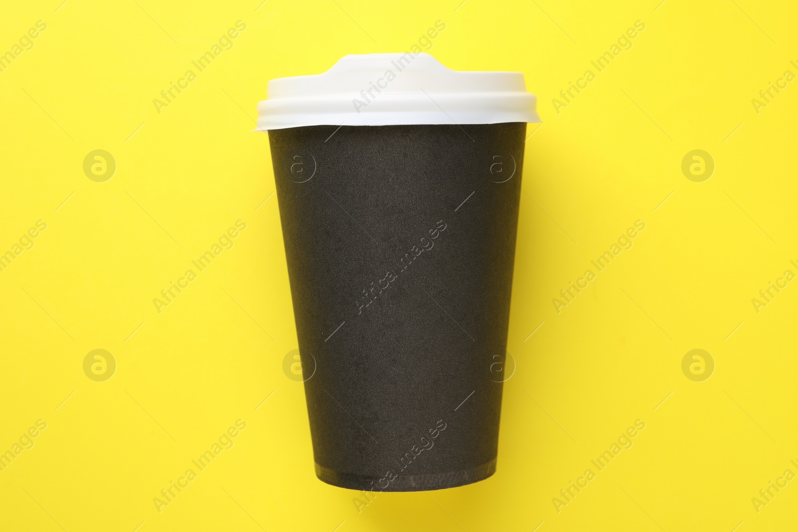 Photo of One paper cup on yellow background, top view. Coffee to go