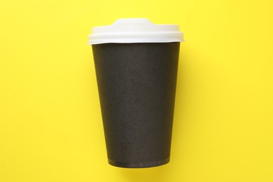 Photo of One paper cup on yellow background, top view. Coffee to go