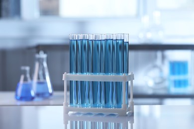 Photo of Test tubes with light blue liquid on table in laboratory