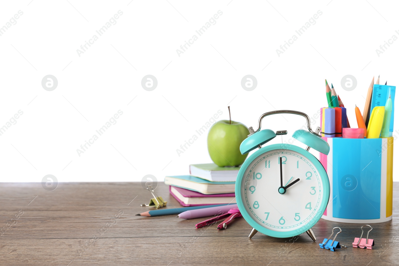 Photo of Turquoise alarm clock and different stationery on wooden table against white background, space for text. School time