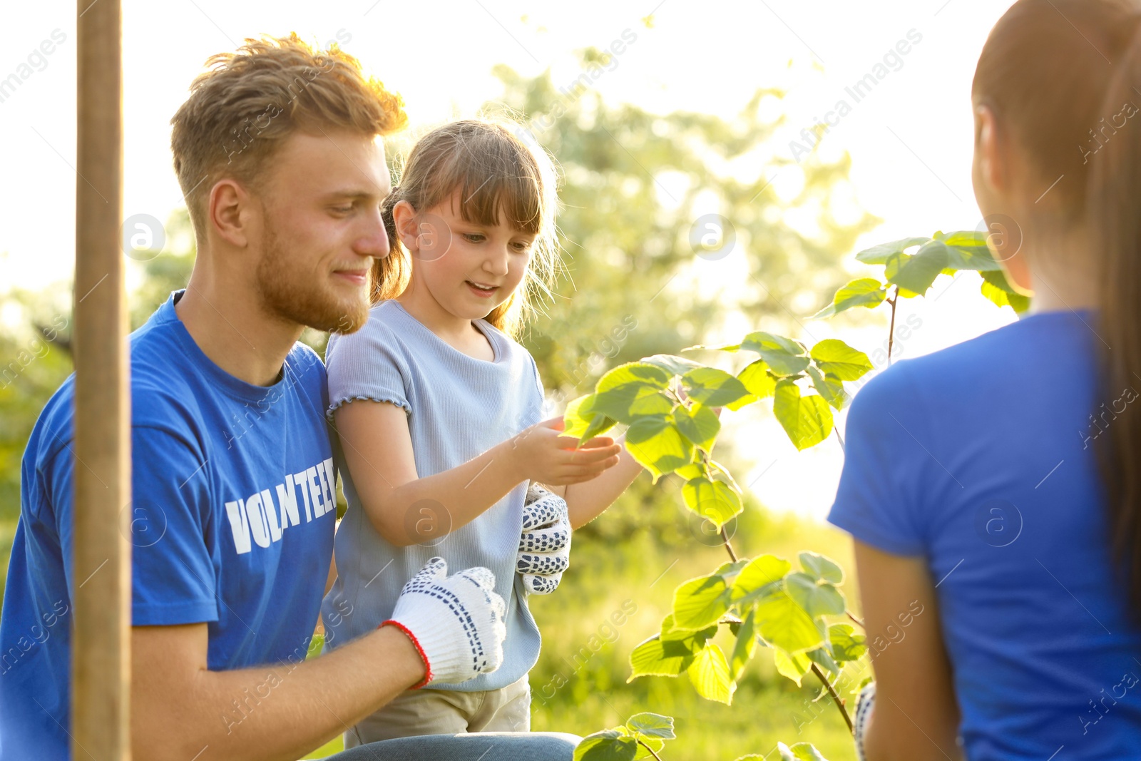 Photo of Little girl planting tree with volunteers in park