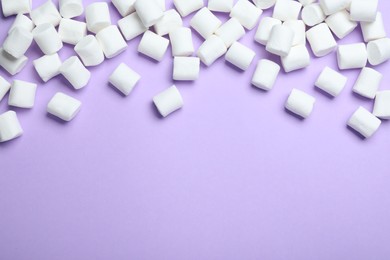 Delicious puffy marshmallows on lilac background, flat lay. Space for text