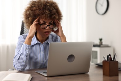 Woman suffering from headache at workplace in office