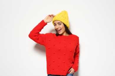 Young woman in warm sweater and hat on white background. Celebrating Christmas