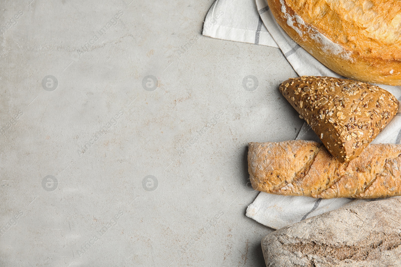 Photo of Loaves of different breads on light background, flat lay. Space for text