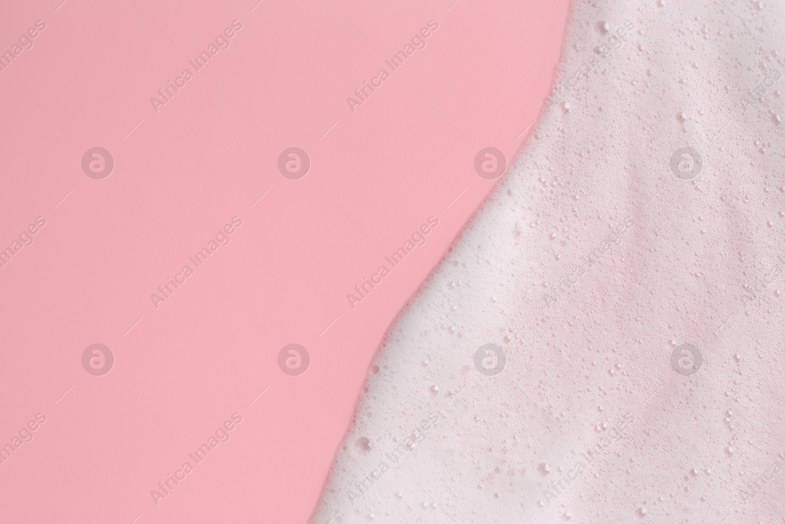 Photo of White fluffy foam on pink background, top view. Space for text