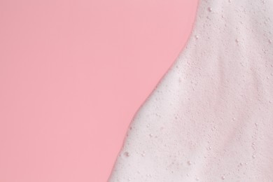 Photo of White fluffy foam on pink background, top view. Space for text