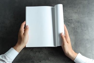 Photo of Man holding blank notebook at black textured table, top view. Mockup for design