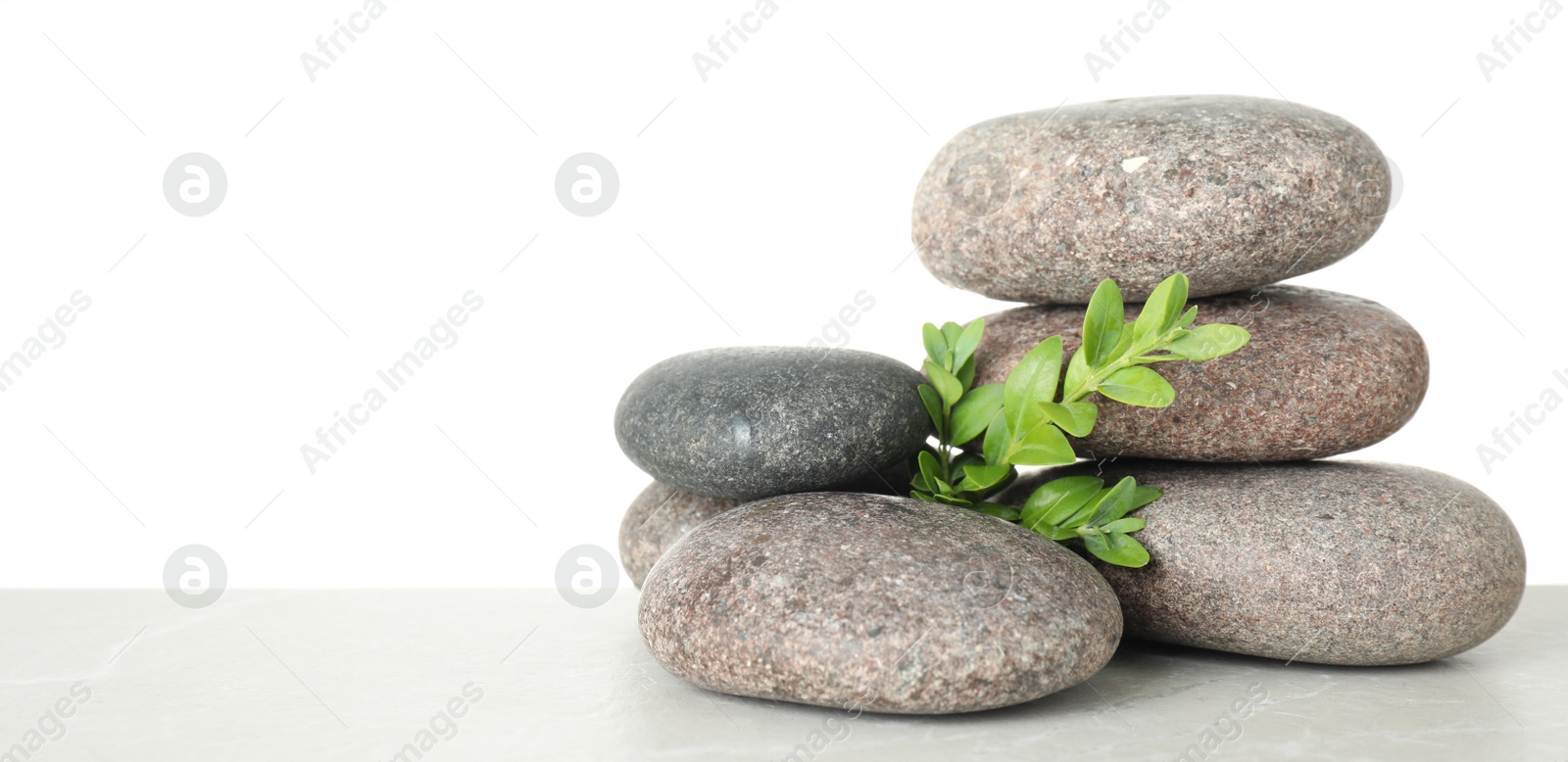 Photo of Stack of spa stones and leaves on table against white background. Space for text