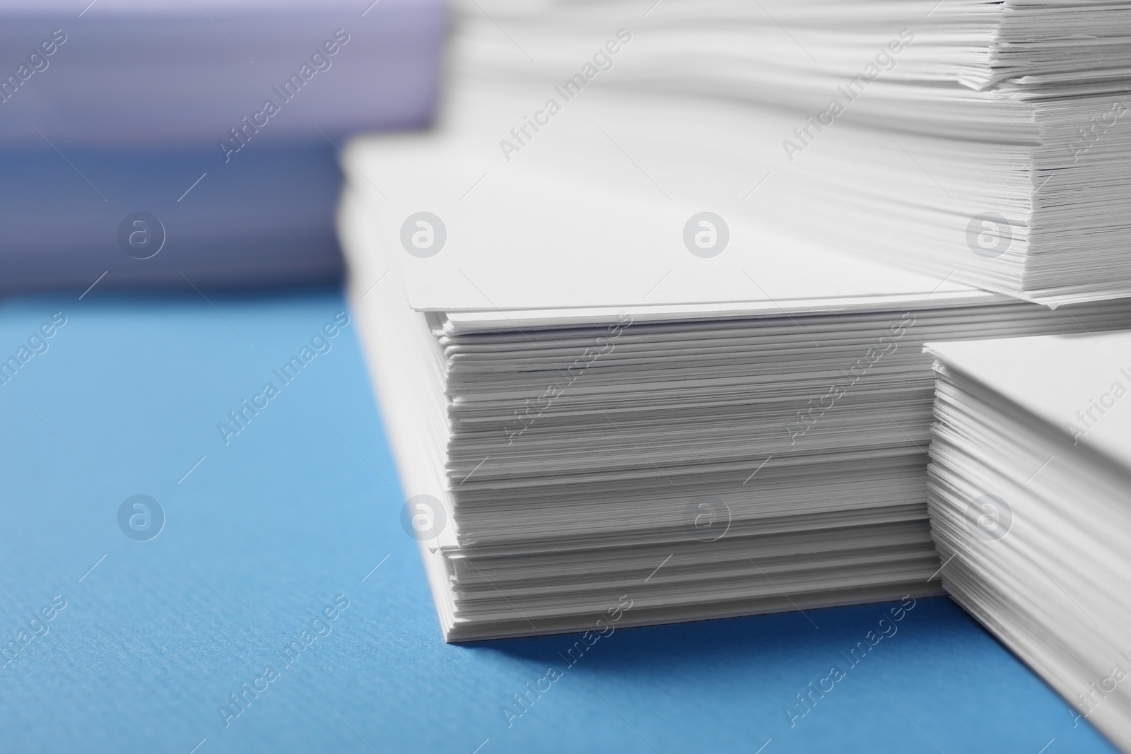 Photo of Many stacks of paper sheets on light blue background, closeup