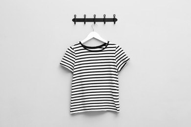Photo of Hanger with striped T-shirt on light grey wall