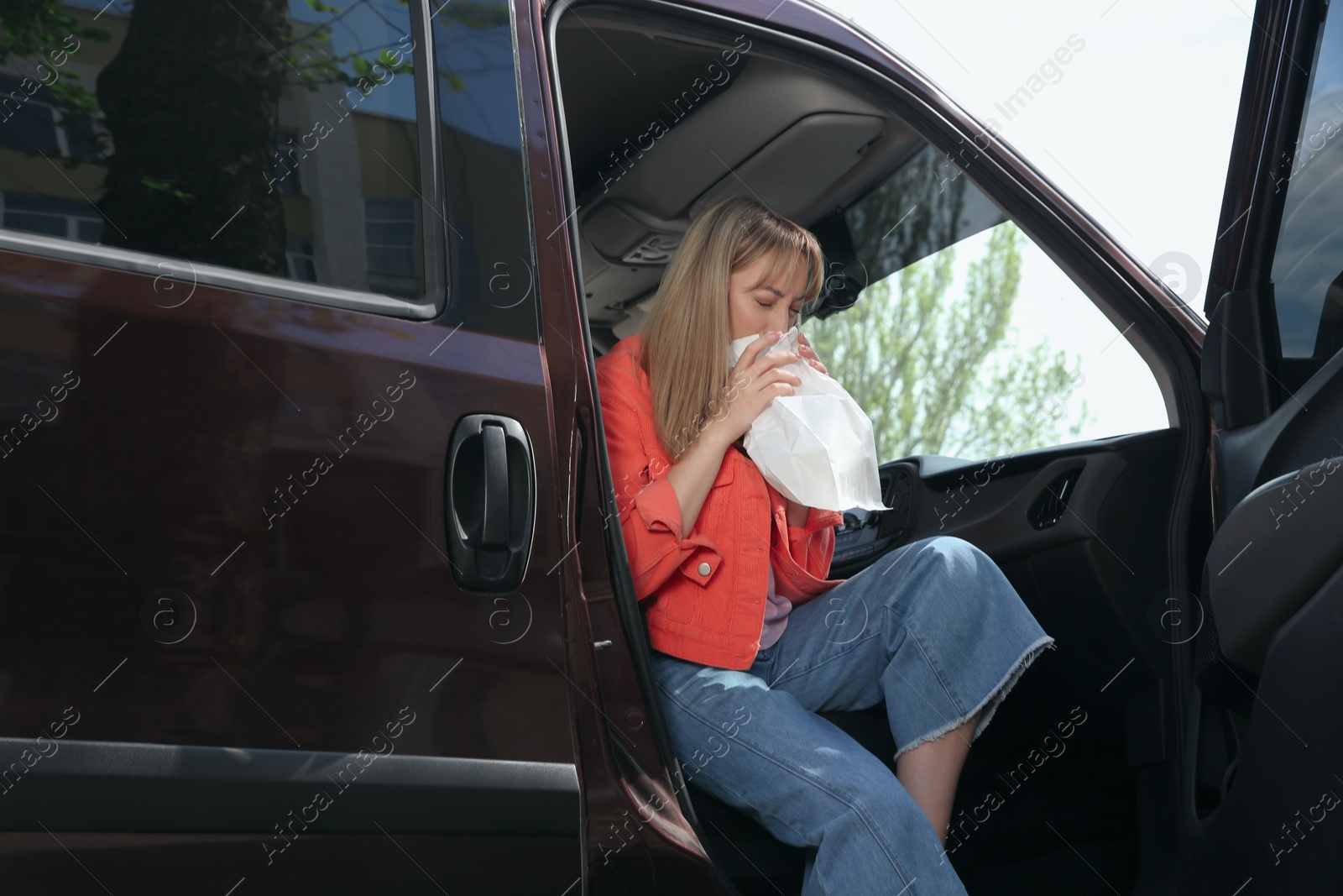 Photo of Woman with paper bag suffering from nausea in car