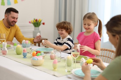 Happy family celebrating Easter at served table in room