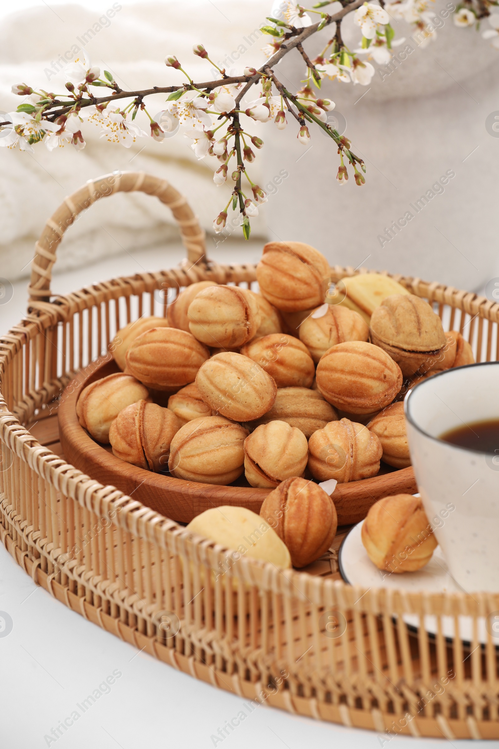 Photo of Delicious walnut shaped cookies with filling, cherry branch and cup of coffee on white table. Homemade popular biscuits from childhood