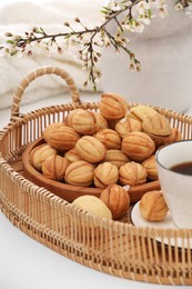 Photo of Delicious walnut shaped cookies with filling, cherry branch and cupcoffee on white table. Homemade popular biscuits from childhood
