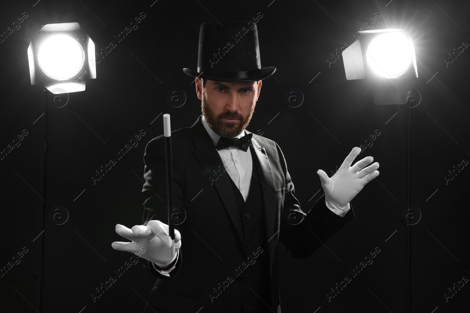 Photo of Magician wearing top hat and holding wand on stage