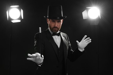Magician wearing top hat and holding wand on stage