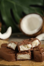 Photo of Delicious milk chocolate candy bars with coconut filling on table, closeup. Space for text