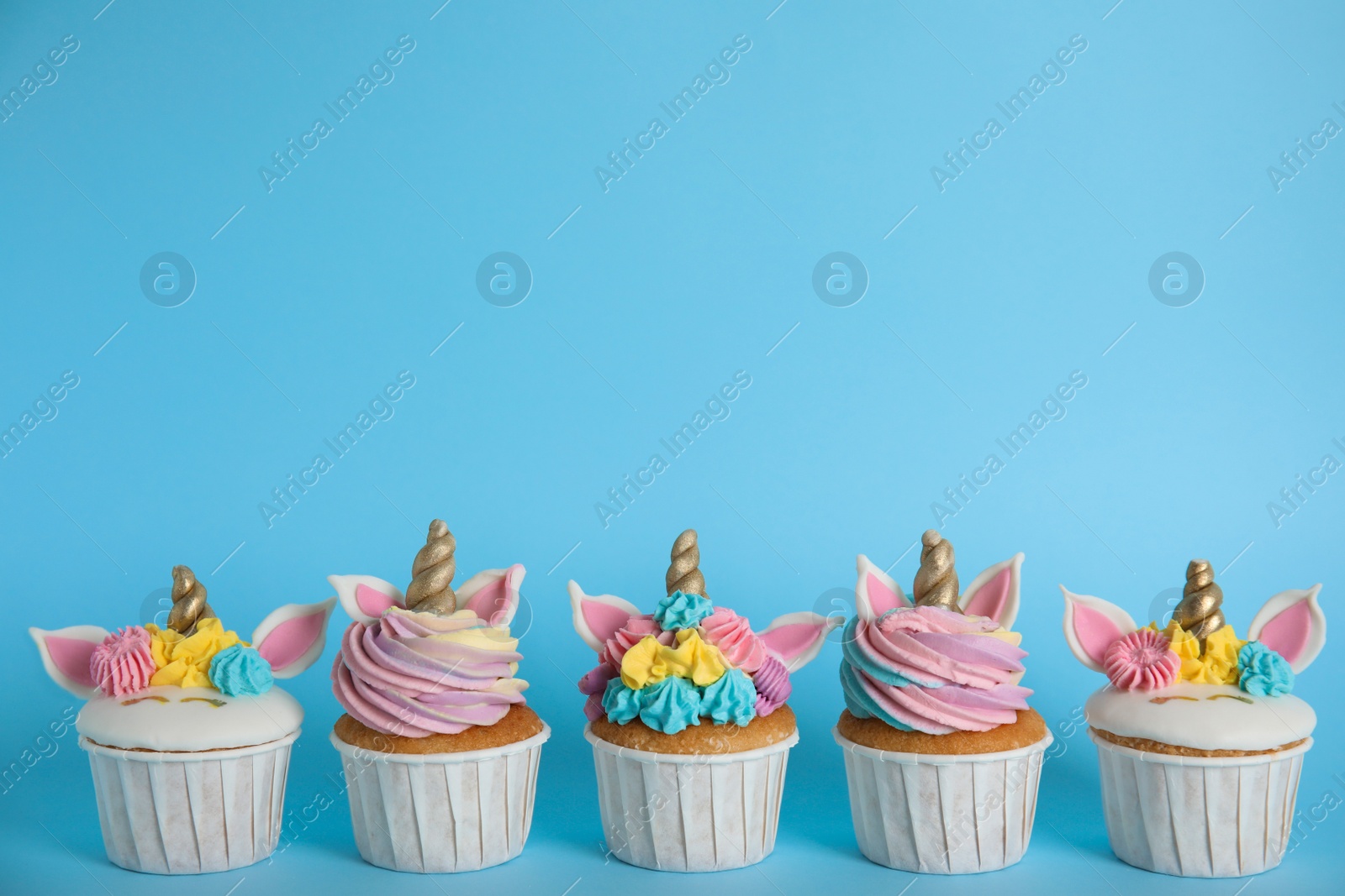 Photo of Many cute sweet unicorn cupcakes on light blue background