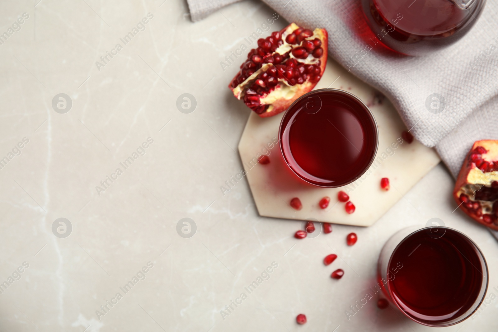 Photo of Glasses of freshly made pomegranate juice on light table, flat lay. Space for text