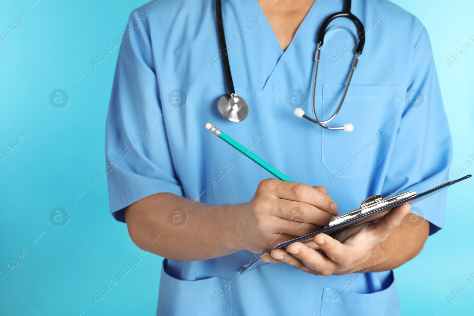 Photo of Male doctor with stethoscope and clipboard on color background, closeup. Medical objects