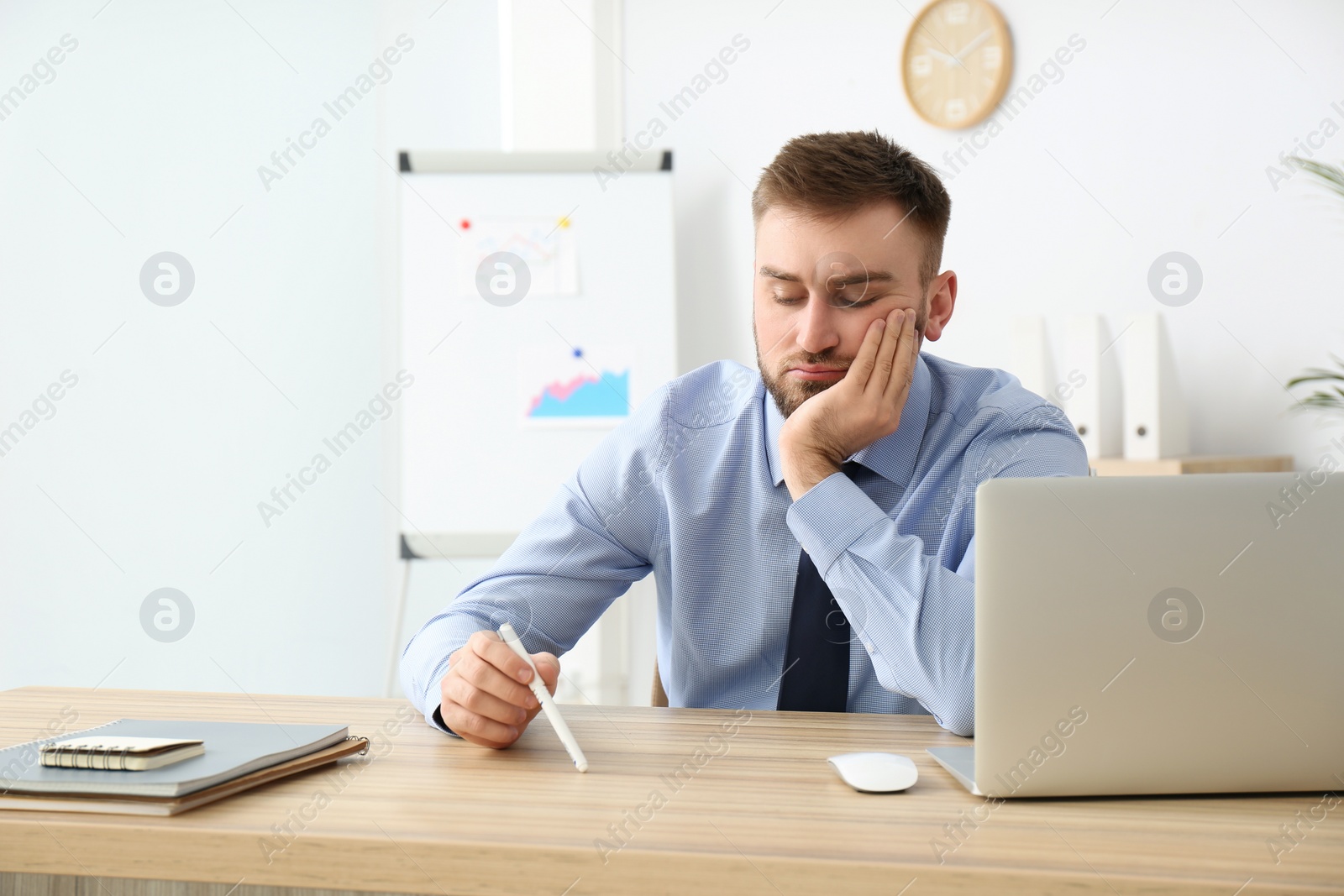 Photo of Lazy young office employee procrastinating at workplace