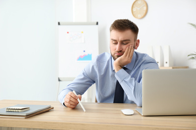 Lazy young office employee procrastinating at workplace