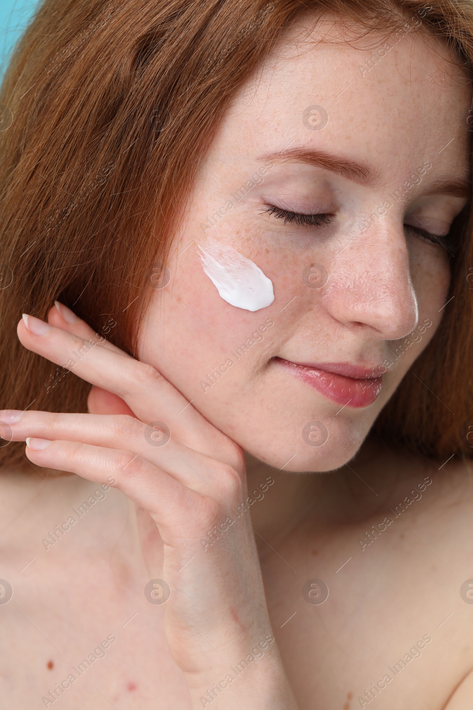 Photo of Beautiful woman with freckles and cream on her face, closeup