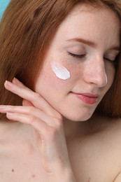 Beautiful woman with freckles and cream on her face, closeup