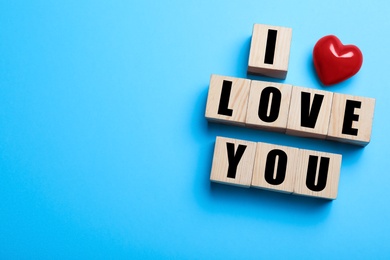 Cubes with words I Love You and red heart on light blue background, flat lay. Space for text