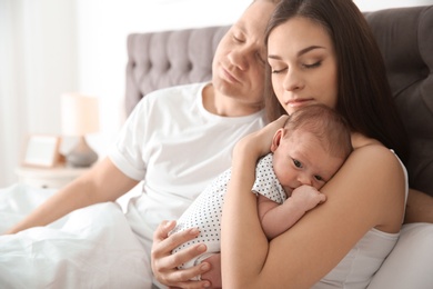 Happy couple with their newborn baby on bed