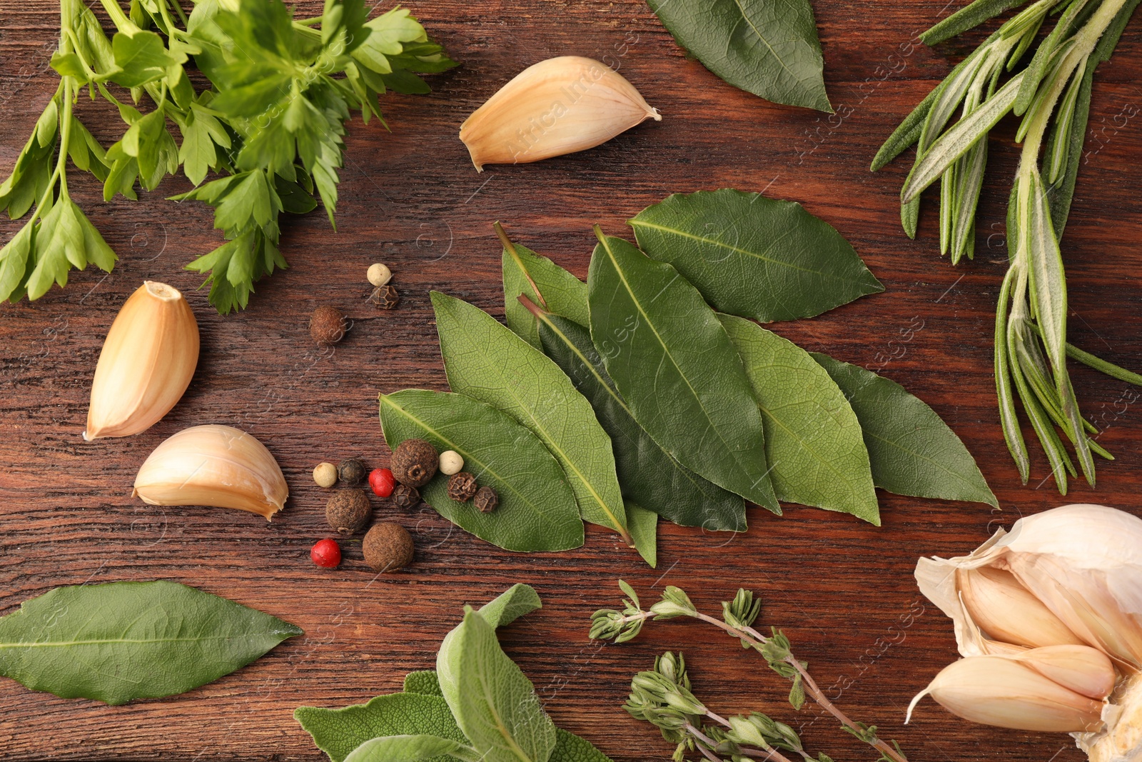 Photo of Aromatic bay leaves, different herbs and spices on wooden table, flat lay