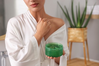 Photo of Young woman applying aloe gel onto her skin in bathroom, closeup